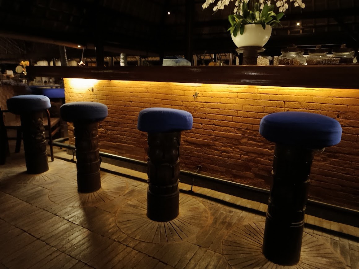Bar with carved wooden stools and warm brick backdrop