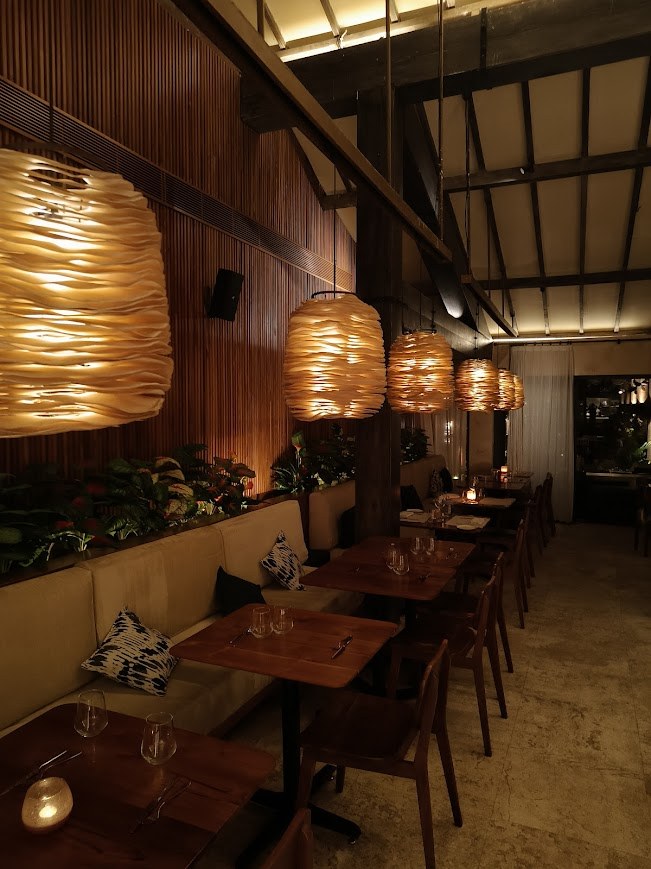 Restaurant with organic wave pendant lights and teak slatted wall