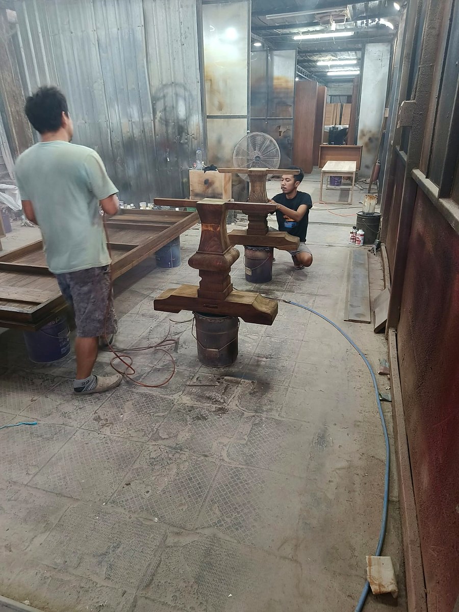 Artisans crafting a teak table base in workshop
